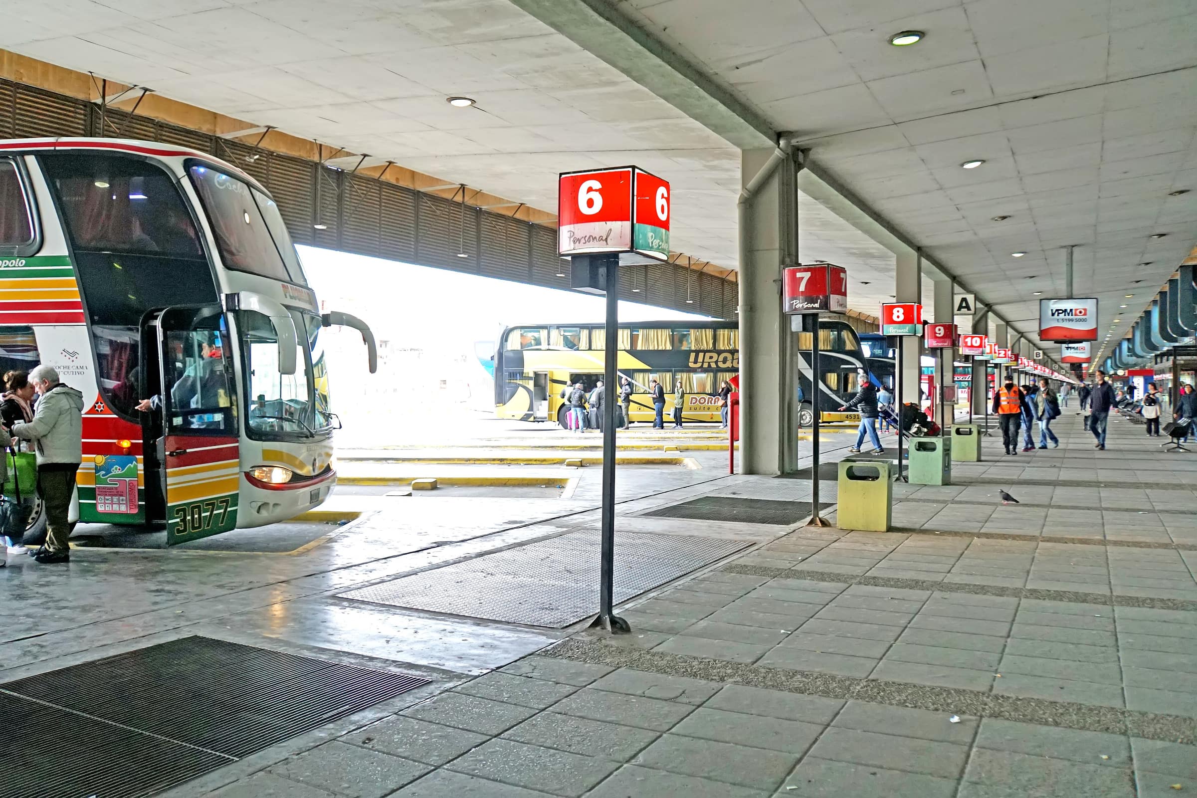 Plataformas de uma rodoviária, com passageiros embarcando nos ônibus